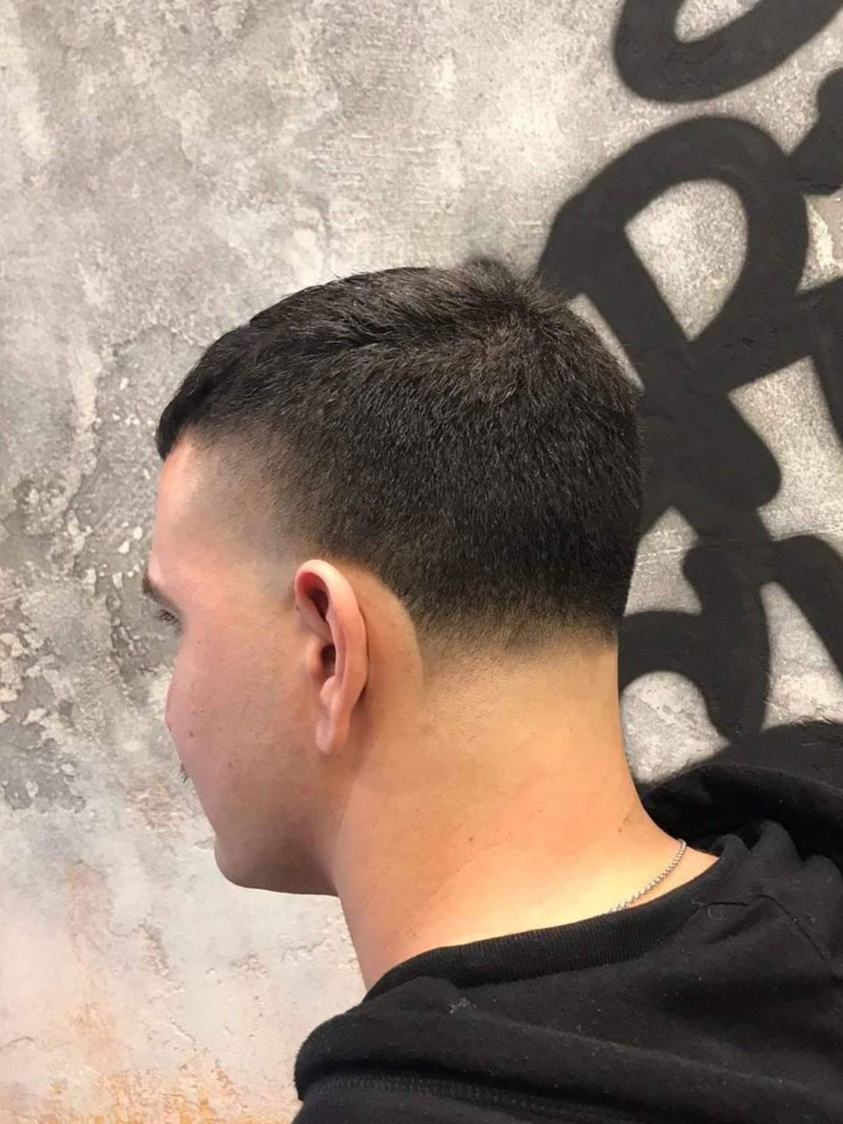 Σγουρό κούρεμα με mid fade, προφίλ, μπροστά στον σκούρο μπλε τοίχο